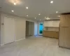 Recessed lighting, wood-finish flooring, white bi-fold closet doors, modern kitchen cabinetry with white upper cabinets, and a built-in stainless steel refrigerator Recessed lighting, wood-finish flooring, white bi-fold closet doors, modern kitchen cabinetry with white upper cabinets, and a built-in stainless steel refrigerator