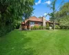 Expansive green lawn, mature trees, wood-sided exterior, stone chimney, and a multi-level wood deck Expansive green lawn, mature trees, wood-sided exterior, stone chimney, and a multi-level wood deck