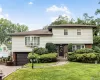Split-level residence featuring brick and shake siding, an attached garage, a bay window, and a paver driveway Split-level residence featuring brick and shake siding, an attached garage, a bay window, and a paver driveway