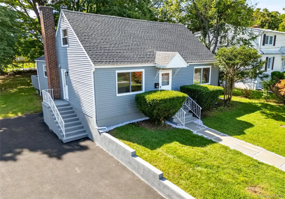 Gray siding exterior with white trim, a gabled roof, and a prominent brick chimney Gray siding exterior with white trim, a gabled roof, and a prominent brick chimney
