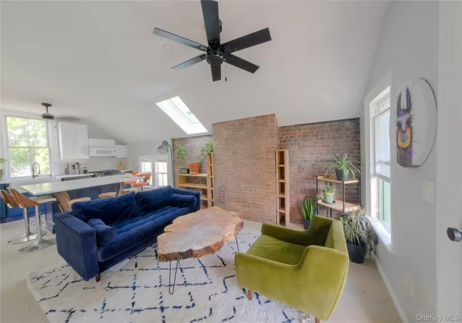 Vaulted ceiling with skylights, exposed brick wall, and a ceiling fan Vaulted ceiling with skylights, exposed brick wall, and a ceiling fan