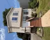 Two-story home with light-toned siding, a front entry deck, and a concrete pathway Two-story home with light-toned siding, a front entry deck, and a concrete pathway