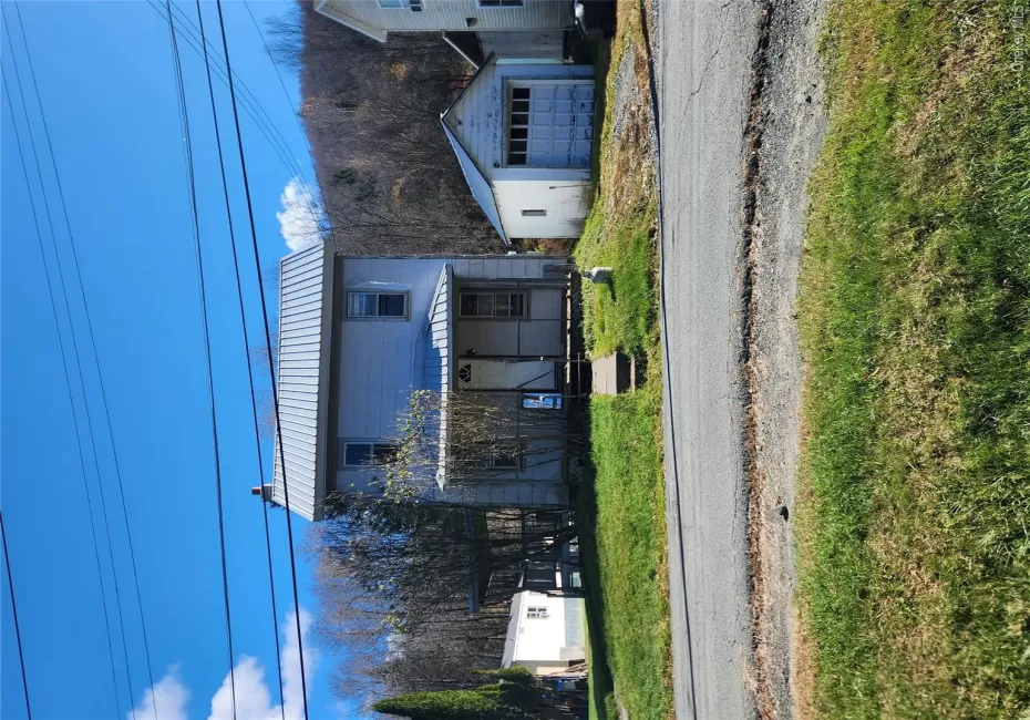 View of front of home with an outdoor structure, a metal roof, a garage, a porch, and a front lawn View of front of home with an outdoor structure, a metal roof, a garage, a porch, and a front lawn