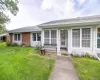 Front facade featuring a storm door entrance, multiple windows, brick and siding exterior, and a concrete pathway Front facade featuring a storm door entrance, multiple windows, brick and siding exterior, and a concrete pathway