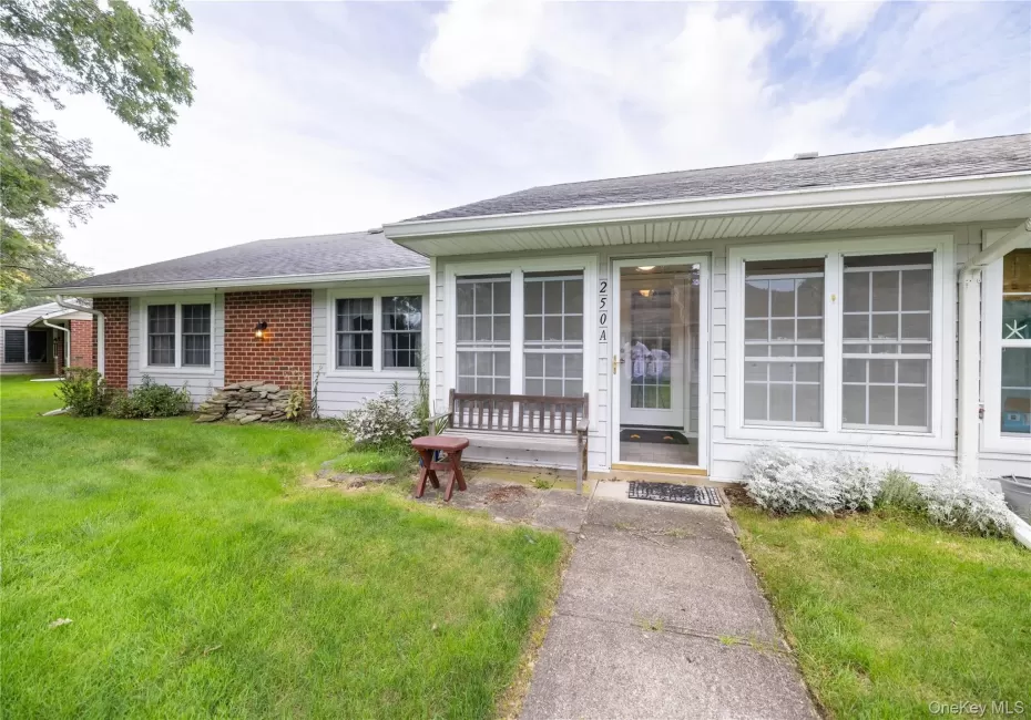 Front facade featuring a storm door entrance, multiple windows, brick and siding exterior, and a concrete pathway Front facade featuring a storm door entrance, multiple windows, brick and siding exterior, and a concrete pathway
