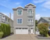 Three-story home with stone accents, featuring a paver driveway, and Juliette balconies Three-story home with stone accents, featuring a paver driveway, and Juliette balconies