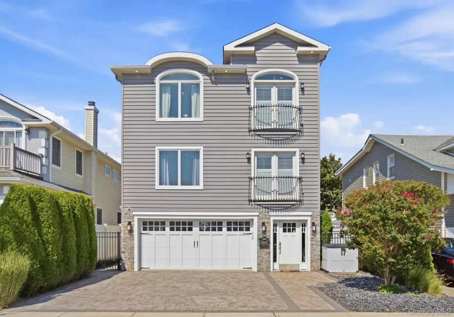 Three-story home with stone accents, featuring a paver driveway, and Juliette balconies Three-story home with stone accents, featuring a paver driveway, and Juliette balconies