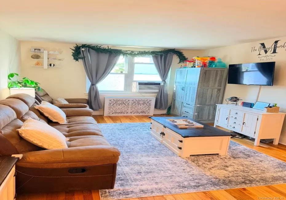Hardwood flooring, window with natural light, wall-mounted television, and a decorative radiator cover Hardwood flooring, window with natural light, wall-mounted television, and a decorative radiator cover