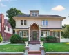 Traditional-style home featuring a brick and stucco facade, a prominent front entrance with stone accents, a dormer window, mature landscaping, and a manicured lawn Traditional-style home featuring a brick and stucco facade, a prominent front entrance with stone accents, a dormer window, mature landscaping, and a manicured lawn