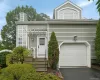 Siding exterior with a paneled garage door, arched window, and a white front entry door with an overhead pergola Siding exterior with a paneled garage door, arched window, and a white front entry door with an overhead pergola