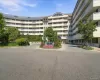 Curved facade with multiple levels of private balconies, accented by a prominent entrance and lush landscaping Curved facade with multiple levels of private balconies, accented by a prominent entrance and lush landscaping