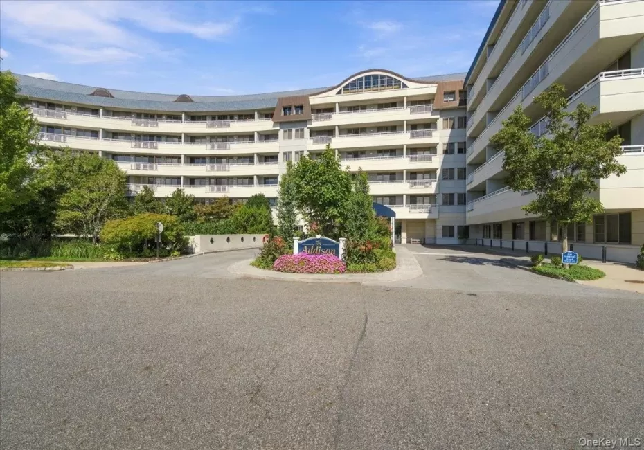 Curved facade with multiple levels of private balconies, accented by a prominent entrance and lush landscaping Curved facade with multiple levels of private balconies, accented by a prominent entrance and lush landscaping