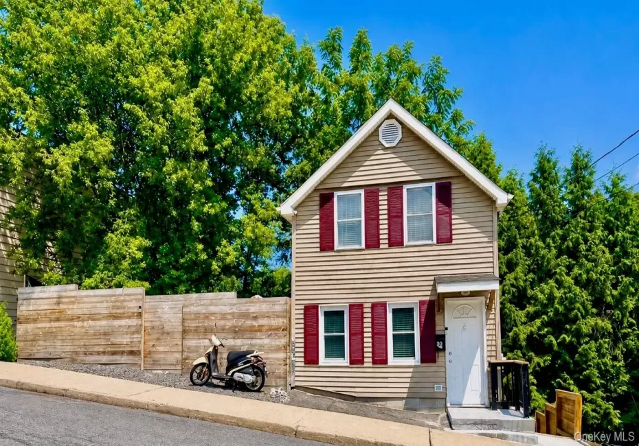 Two-story dwelling with horizontal siding, a gabled roof, and red louvered shutters Two-story dwelling with horizontal siding, a gabled roof, and red louvered shutters