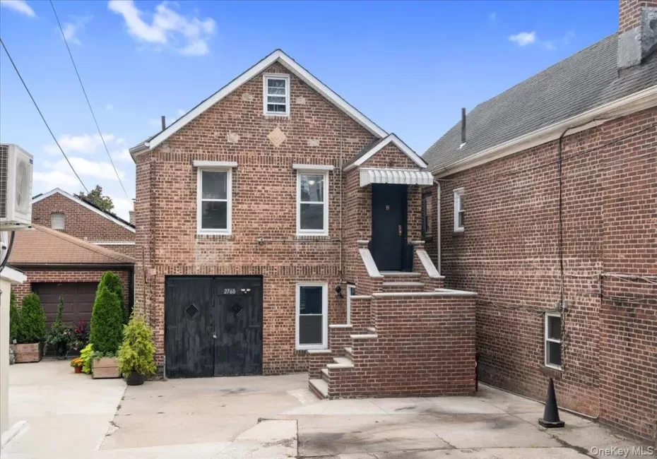 Brick exterior with a peaked roof, multiple windows, and a dark entry door Brick exterior with a peaked roof, multiple windows, and a dark entry door