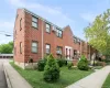 Brick exterior with multiple windows, front yard with green lawn, concrete sidewalk, and established landscaping Brick exterior with multiple windows, front yard with green lawn, concrete sidewalk, and established landscaping