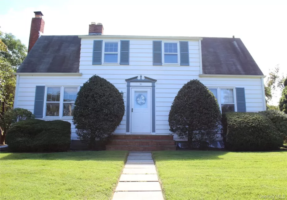 White siding exterior with a gambrel roof and two prominent brick chimneys White siding exterior with a gambrel roof and two prominent brick chimneys