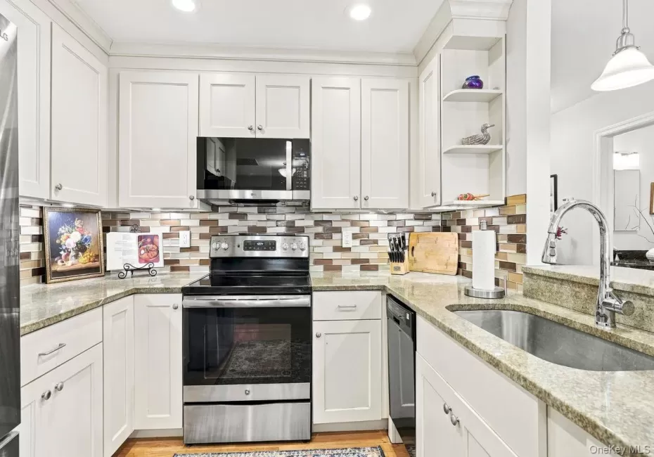 White shaker-style cabinetry, granite countertops, mosaic tile backsplash, stainless steel appliances, and an undermount sink with a gooseneck faucet White shaker-style cabinetry, granite countertops, mosaic tile backsplash, stainless steel appliances, and an undermount sink with a gooseneck faucet