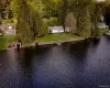 Waterfront property with a stone retaining wall, mature trees, and a detached boathouse Waterfront property with a stone retaining wall, mature trees, and a detached boathouse