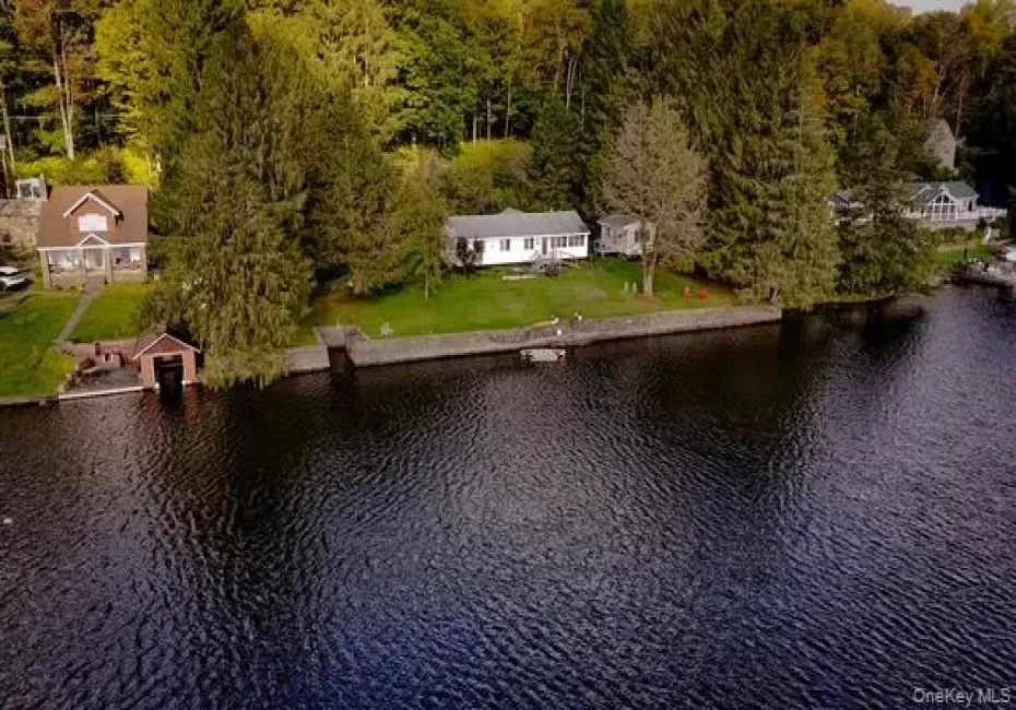 Waterfront property with a stone retaining wall, mature trees, and a detached boathouse Waterfront property with a stone retaining wall, mature trees, and a detached boathouse