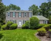 Traditional exterior with beige siding, dark shutters, a white front door, and a well-maintained lawn Traditional exterior with beige siding, dark shutters, a white front door, and a well-maintained lawn