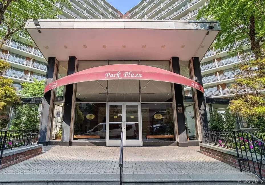 Building entrance featuring a red awning, full-height glass doors, and a paver walkway Building entrance featuring a red awning, full-height glass doors, and a paver walkway