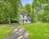 White siding exterior, dark shingle roof, paved circular driveway, expansive green lawn, mature trees White siding exterior, dark shingle roof, paved circular driveway, expansive green lawn, mature trees