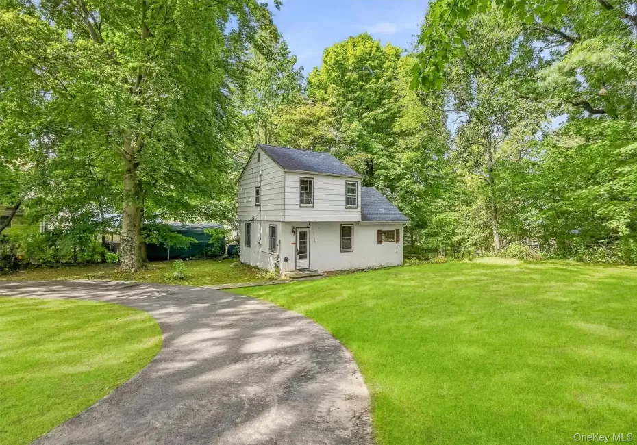 White siding exterior, dark shingle roof, paved circular driveway, expansive green lawn, mature trees White siding exterior, dark shingle roof, paved circular driveway, expansive green lawn, mature trees