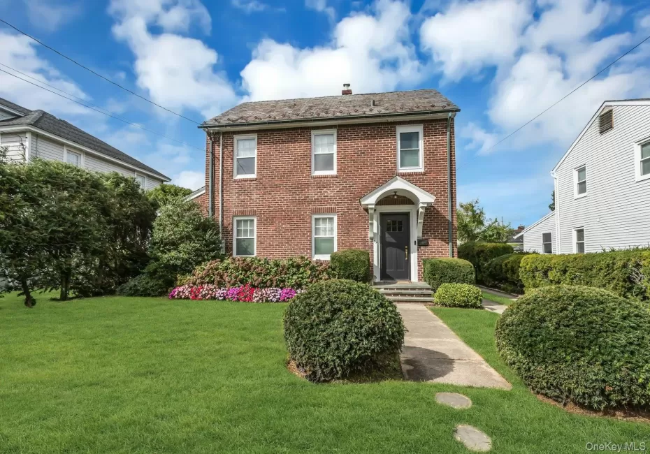 Brick exterior with white window trim, covered entry, and dark-paneled front door Brick exterior with white window trim, covered entry, and dark-paneled front door
