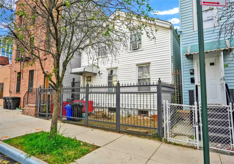 White siding exterior with a dark ornamental fence and a light-colored awning over the entrance White siding exterior with a dark ornamental fence and a light-colored awning over the entrance