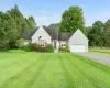 New england style home with driveway, a front yard, a shingled roof, and a garage New england style home with driveway, a front yard, a shingled roof, and a garage