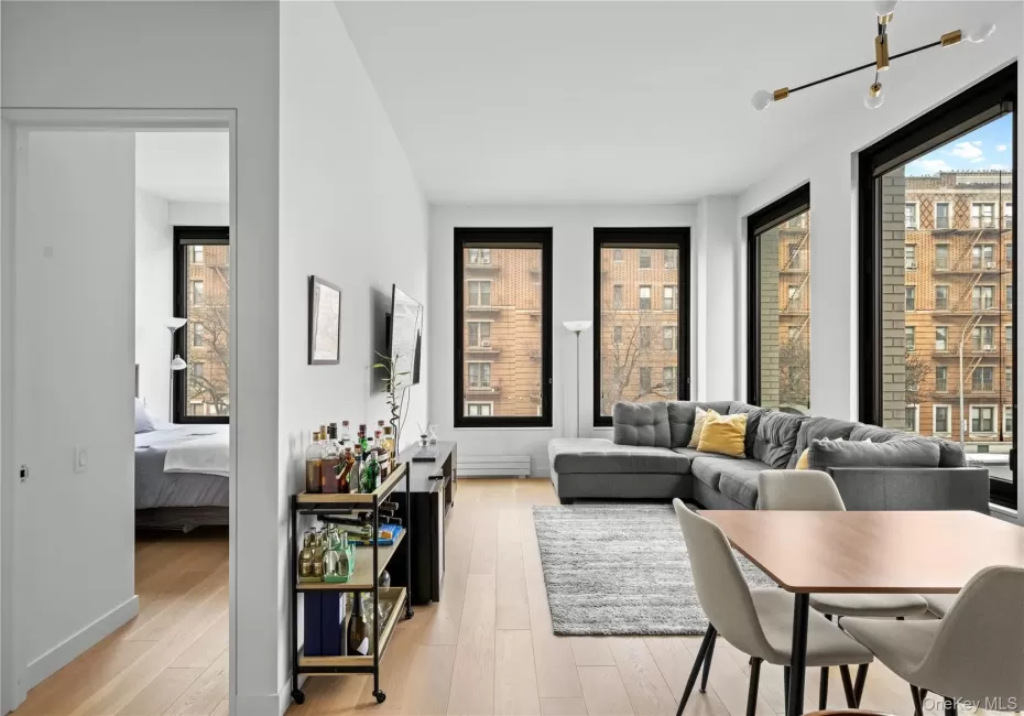 Living room with light wood-style floors, plenty of natural light, and a baseboard heating unit Living room with light wood-style floors, plenty of natural light, and a baseboard heating unit