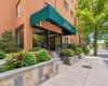 Brick facade building featuring a green awning, stone-clad planters, wrought iron railings, and extensive landscaping Brick facade building featuring a green awning, stone-clad planters, wrought iron railings, and extensive landscaping