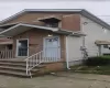 Brick and siding exterior featuring multiple awnings, a concrete walkway, and a porch with metal railings Brick and siding exterior featuring multiple awnings, a concrete walkway, and a porch with metal railings