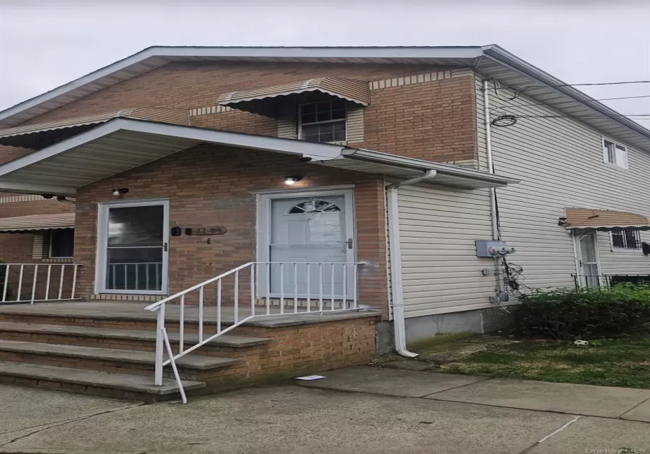 Brick and siding exterior featuring multiple awnings, a concrete walkway, and a porch with metal railings Brick and siding exterior featuring multiple awnings, a concrete walkway, and a porch with metal railings