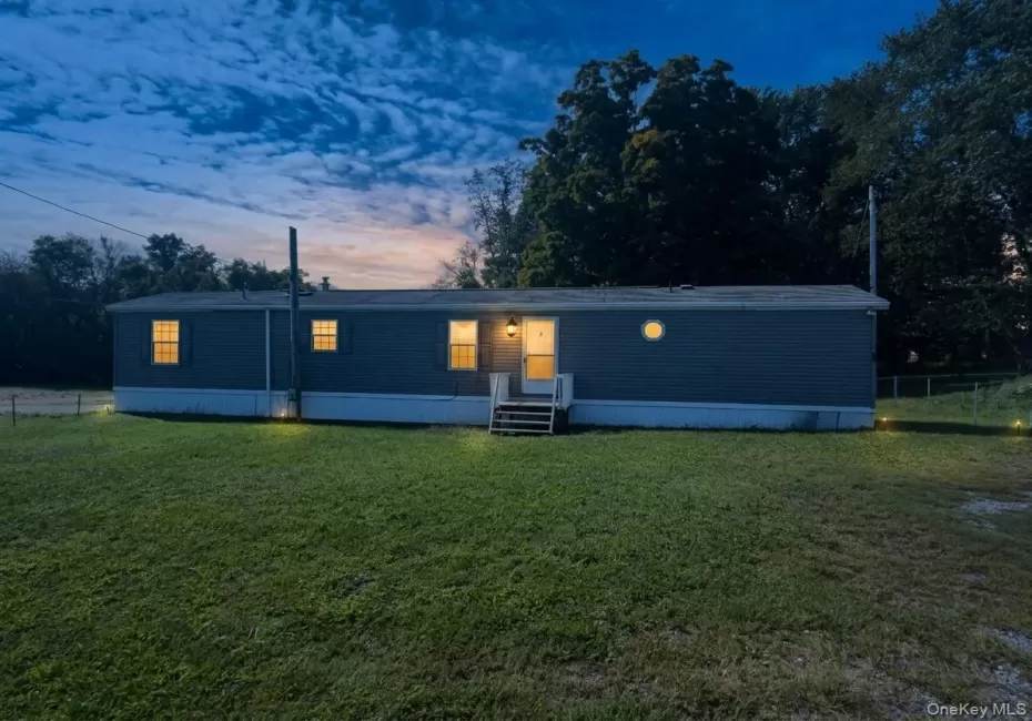 Single-story residence featuring horizontal siding, multiple windows, a prominent entry light, and a front porch with stairs Single-story residence featuring horizontal siding, multiple windows, a prominent entry light, and a front porch with stairs