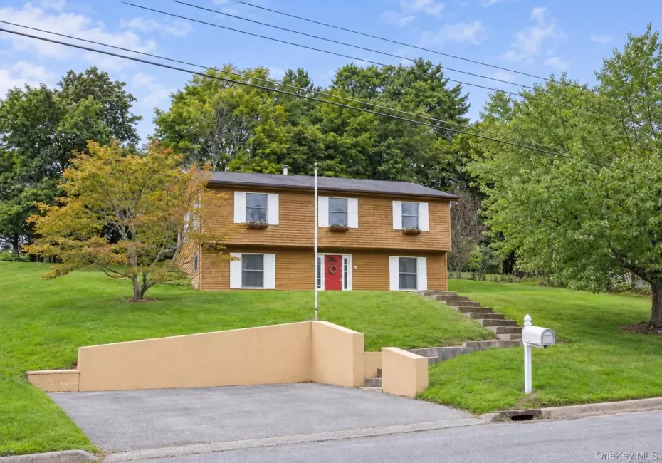 Wood-sided exterior with white window shutters and a red entry door Wood-sided exterior with white window shutters and a red entry door