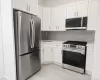 Kitchen featuring white shaker cabinetry, stainless steel appliances, light-toned countertops, subway tile backsplash, and light wood-finish flooring Kitchen featuring white shaker cabinetry, stainless steel appliances, light-toned countertops, subway tile backsplash, and light wood-finish flooring