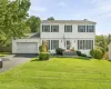 White siding exterior with dark shutters, attached two-car garage, and established front landscaping White siding exterior with dark shutters, attached two-car garage, and established front landscaping