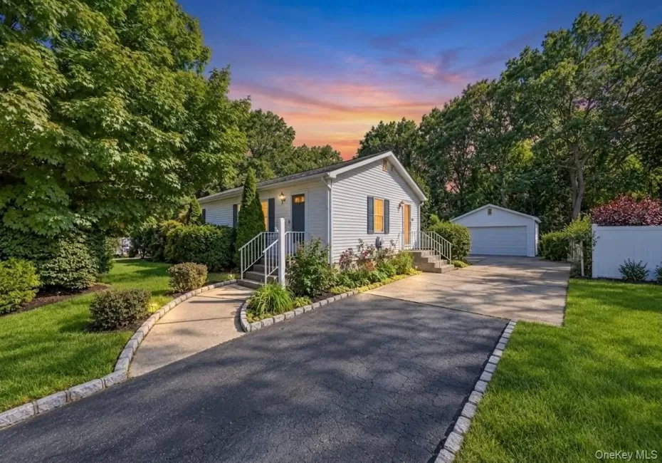 Exterior featuring siding, mature trees, a paved driveway, and a detached garage Exterior featuring siding, mature trees, a paved driveway, and a detached garage