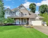 Two-story residence featuring light-colored siding and a covered front porch Two-story residence featuring light-colored siding and a covered front porch