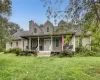 Expansive front lawn leading to a welcoming covered porch, dormer windows, and a prominent chimney Expansive front lawn leading to a welcoming covered porch, dormer windows, and a prominent chimney