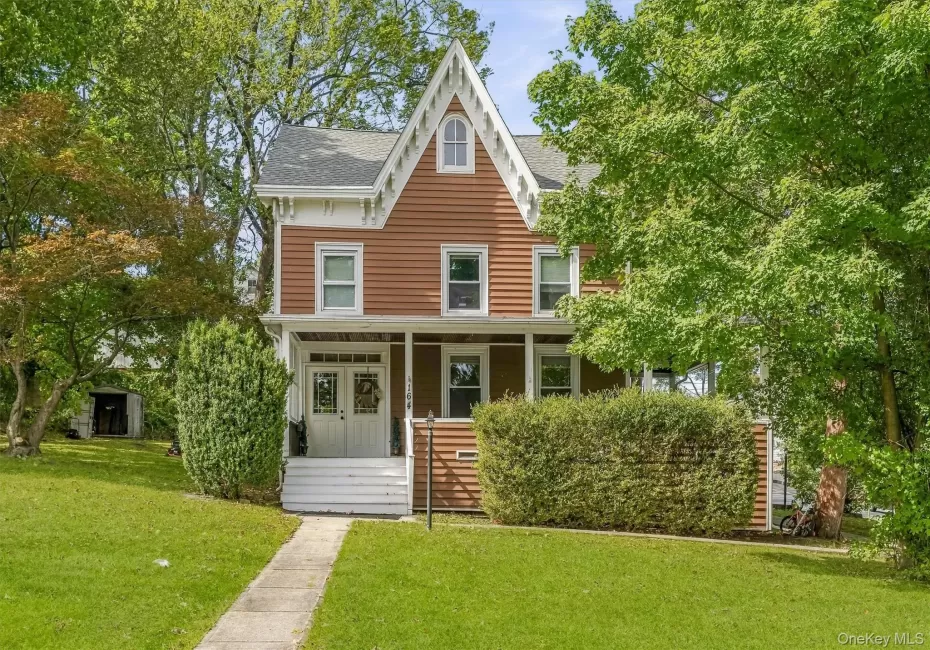 Gabled roofline, front porch, double entry doors, front lawn, and mature trees Gabled roofline, front porch, double entry doors, front lawn, and mature trees
