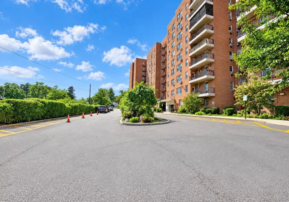 Brick-clad building with multiple private balconies, a circular driveway, and mature perimeter landscaping Brick-clad building with multiple private balconies, a circular driveway, and mature perimeter landscaping