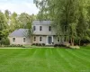 Two-story colonial residence with light tan siding, a dark gray shingle roof, and white-framed windows Two-story colonial residence with light tan siding, a dark gray shingle roof, and white-framed windows