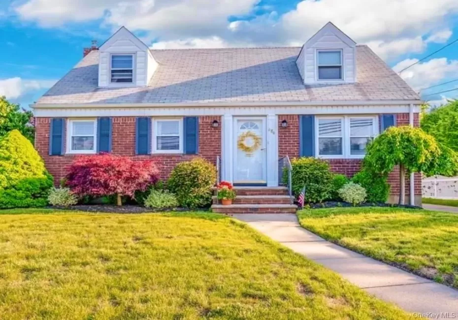 Cape cod-style house with brick siding and a front yard Cape cod-style house with brick siding and a front yard