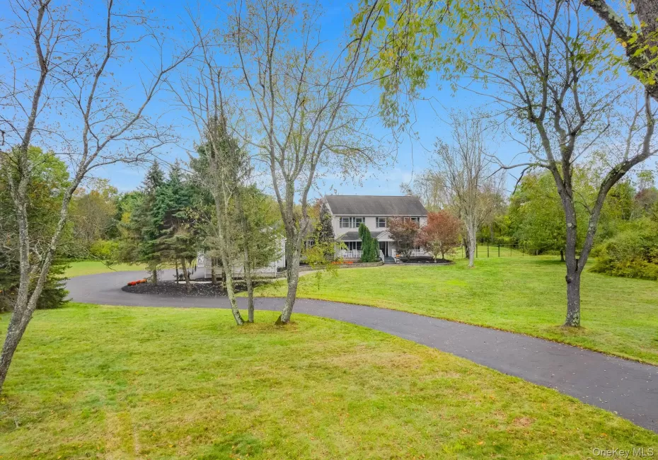Expansive grassy lawn with established landscaping and mature trees and colonial style house with fencing. Expansive grassy lawn with established landscaping and mature trees and colonial style house with fencing.
