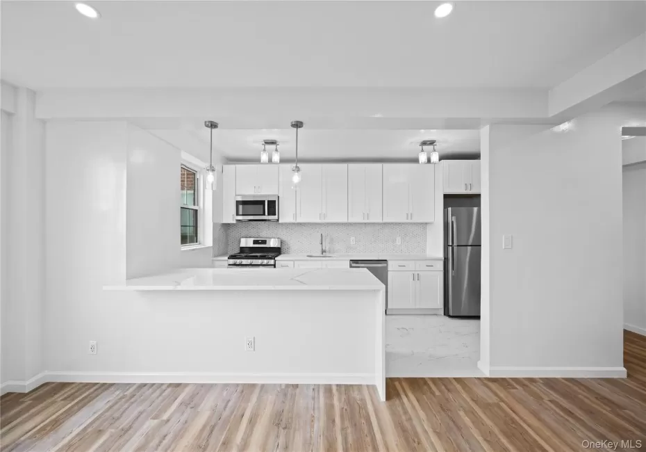 Kitchen featuring stainless steel appliances, recessed lighting, white cabinets, decorative backsplash, and light wood-style floors Kitchen featuring stainless steel appliances, recessed lighting, white cabinets, decorative backsplash, and light wood-style floors