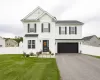 Two-story residence featuring white siding, black shutters, a two-car garage, and a fenced backyard Two-story residence featuring white siding, black shutters, a two-car garage, and a fenced backyard