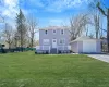 Colonial-style house with an outdoor structure, a detached garage, covered porch, driveway, and a front lawn Colonial-style house with an outdoor structure, a detached garage, covered porch, driveway, and a front lawn
