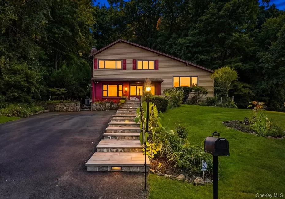 Split-level residence featuring a paved driveway, stone retaining walls, and a multi-level stone walkway. Split-level residence featuring a paved driveway, stone retaining walls, and a multi-level stone walkway.